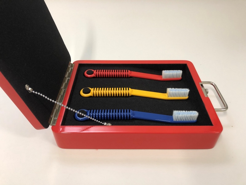 Prototyp till schatull med tre tandborstar (blå, röd, gul). Presentationsmodell