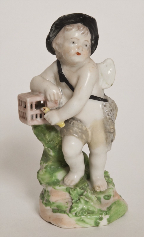 Figurin, bevingad putto med hatt och ländkläde
