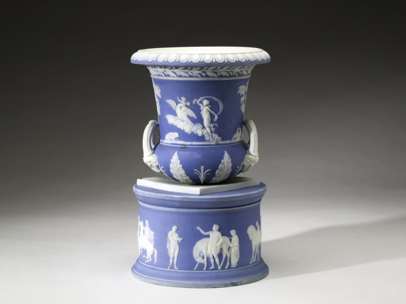 Sockel med urna utan lock i blått med figurgrupper