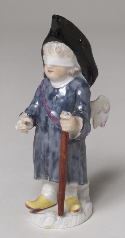Figurin, bevingad putto som blindbock, med bindel för ögonen