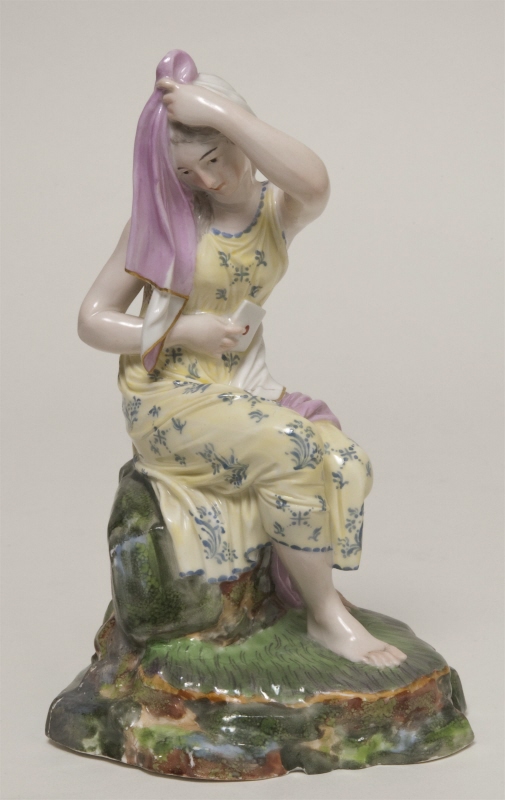 Figurin, flicka sittande på klippblock med brev i handen
