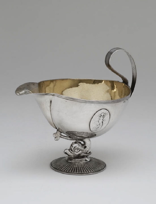 Cream jug in the shape of a bowl resting on a dolphin